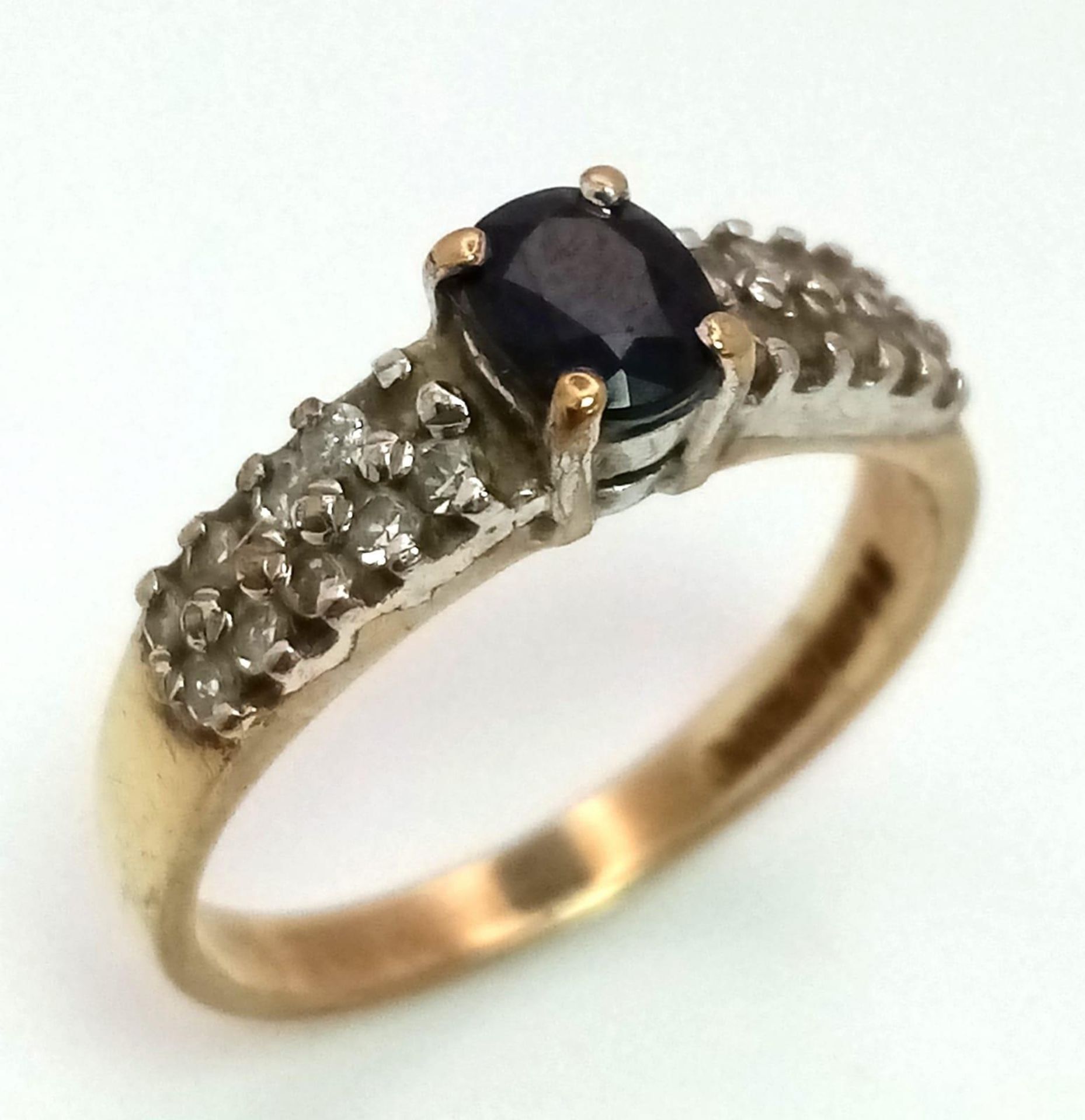 A 9K Yellow Gold Sapphire and Diamond Ring. Central oval sapphire with diamond wings. Size J. 1.