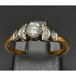 An 18K Yellow Gold Diamond Ring. Central brilliant round cut diamond with two round cut diamonds