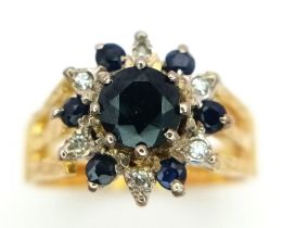 An 18K Yellow Gold Diamond and Sapphire Ring. Central round cut sapphire with an alternating halo of