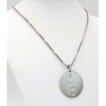 A sterling silver chain necklace with a large round flat pendant carrying oversized British