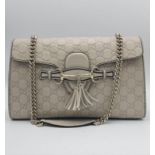 A Gucci Beige 'Emily' Bag. Monogram leather exterior with buckle and tassels. A chunky and heavy set