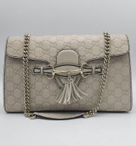 A Gucci Beige 'Emily' Bag. Monogram leather exterior with buckle and tassels. A chunky and heavy set