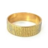 AN 18K GOLD BAND RING WITH PATTERNED EXTERIOR . 3.9gms size 0