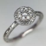 An 18k white gold diamond halo cluster ring with engraved shoulders. 3.2g total weight. Size N 1/