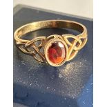 9 carat GOLD RING set to top with an oval cut GARNET. The band having attractive Celtic design