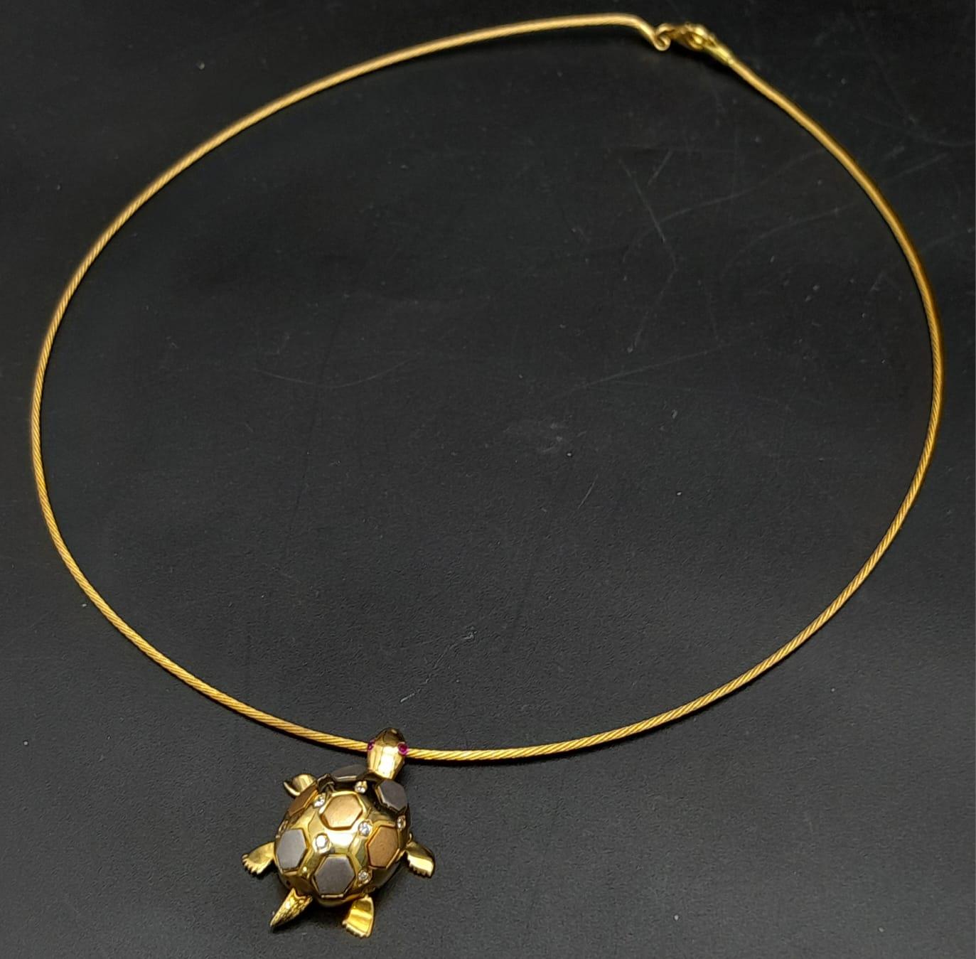 An elegant 18 K yellow gold necklace consisting of a wire rope with a three coloured tortoise