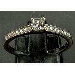 An 18 K yellow and white gold ring with a princess cut diamond (0.37 carats) and further round cut