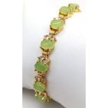 A Green Jade Tennis Bracelet. Oval jade pieces set in gilded metal with white stone decoration.