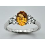 An 18K White Gold, Citrine and Diamond Ring. Oval cut citrine with three bright white round cut