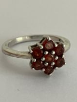 RED TOURMALINE CLUSTER RING Having seven gemstones set in floral/star formation. mounted in 925