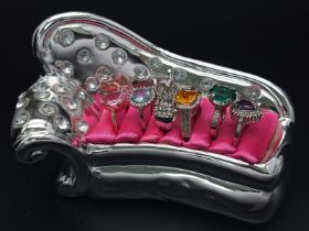 Six dress rings with a variety of gems presented in a miniature chez lounge. Very glamorous!