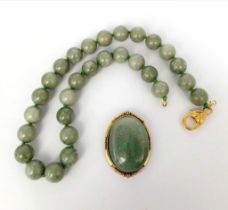 A Green Jade Bead Necklace and Brooch. 14mm beads. 44cm necklace length with a gilded clasp. 5cm