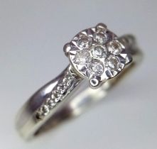 A 9K White Gold Diamond Cluster Ring. Seven small diamonds on a circular base with diamonds on