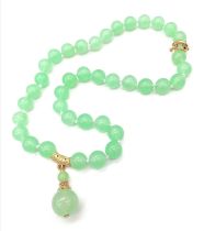 A Green Jade Bead Necklace with Hanging Green Jade Pendant. Gilded accents and clasp. 10mm beads.