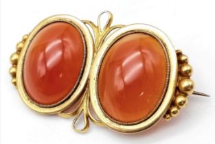 An Antique 18K Yellow Gold (tested) and Carnelian Brooch. Two rich orange cabochons of carnelian set