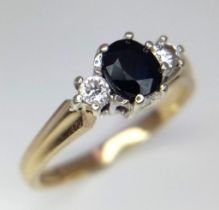 A Vintage 9K Yellow Gold Sapphire and Diamond Ring. Central oval sapphire with a diamond either