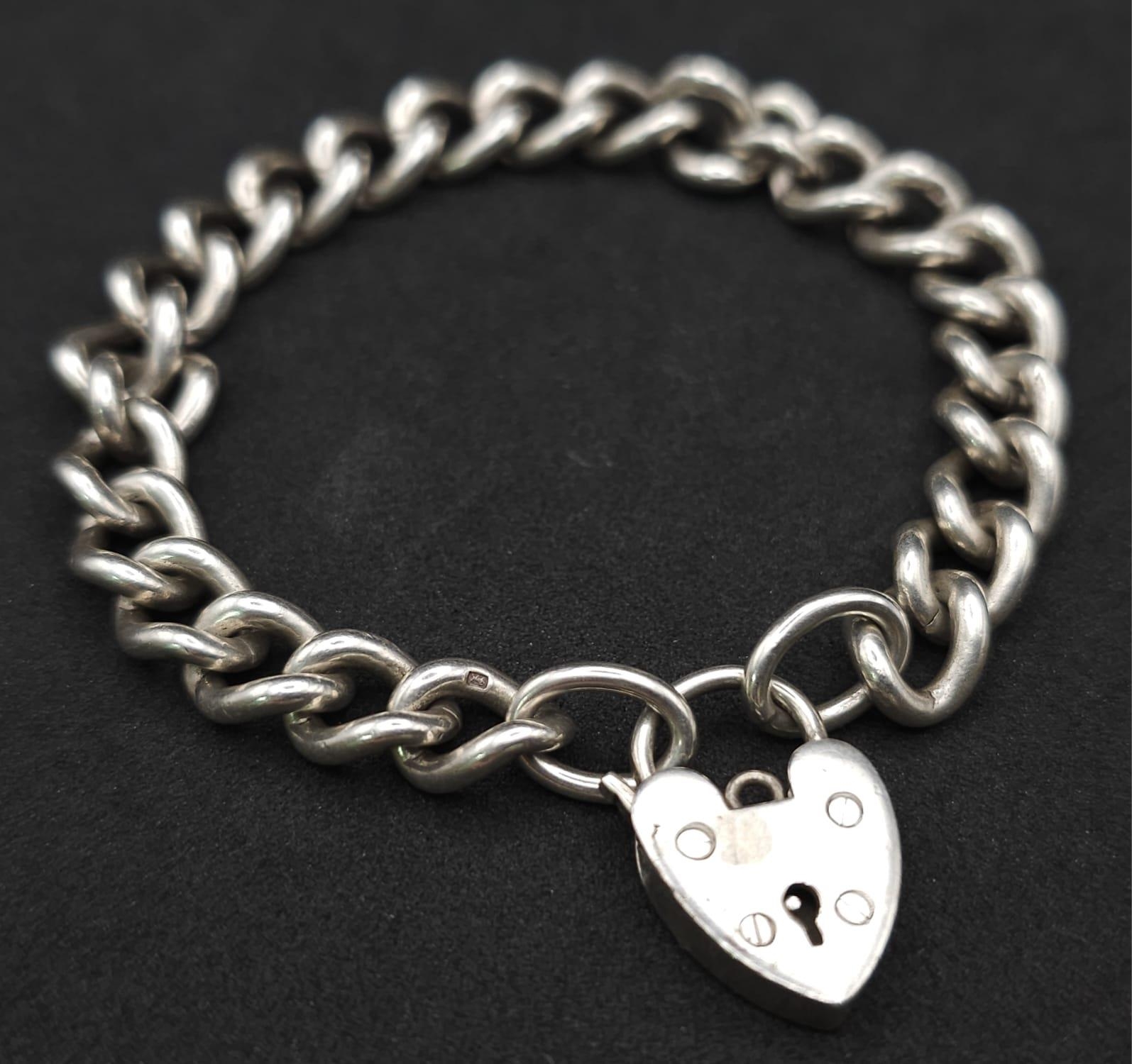 A Sterling silver chunky charm bracelet with heart padlock fastening. 31.6g