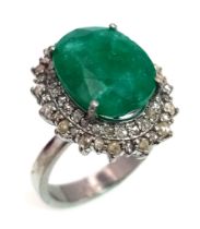 A 6.10ct Emerald Gemstone Ring with 1ct of Diamond Halos. Set in 925 silver. Size N. Comes with a