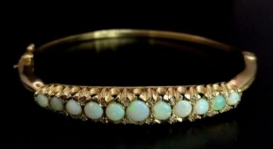 A Beautifully Made 9K Yellow Gold, Opal and Diamond Hinged Bracelet. Eleven opal graduating