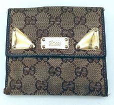 A Gucci Monogram Wallet. Canvas exterior with brown leather trim and gold-tone details. Flap closure