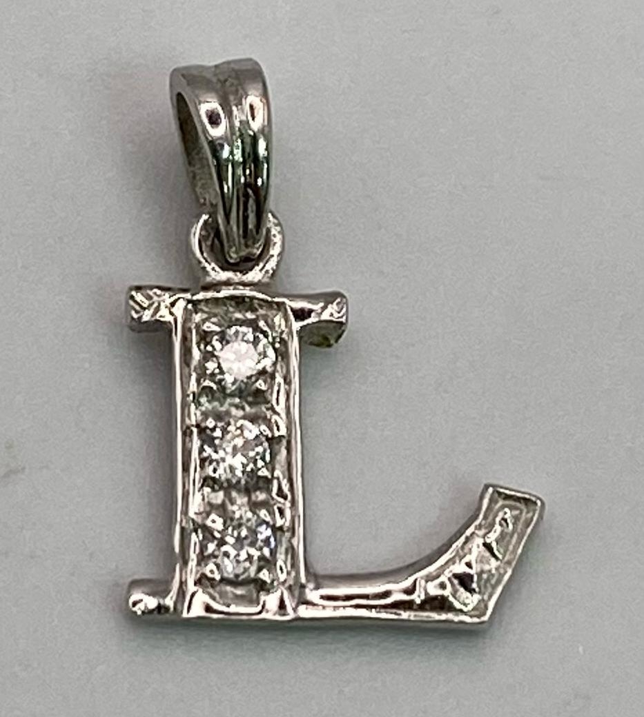 An 18K WHITE GOLD STONE SET INITIAL L PENDANT/CHARM. 1cm length, 0.7g total weight.