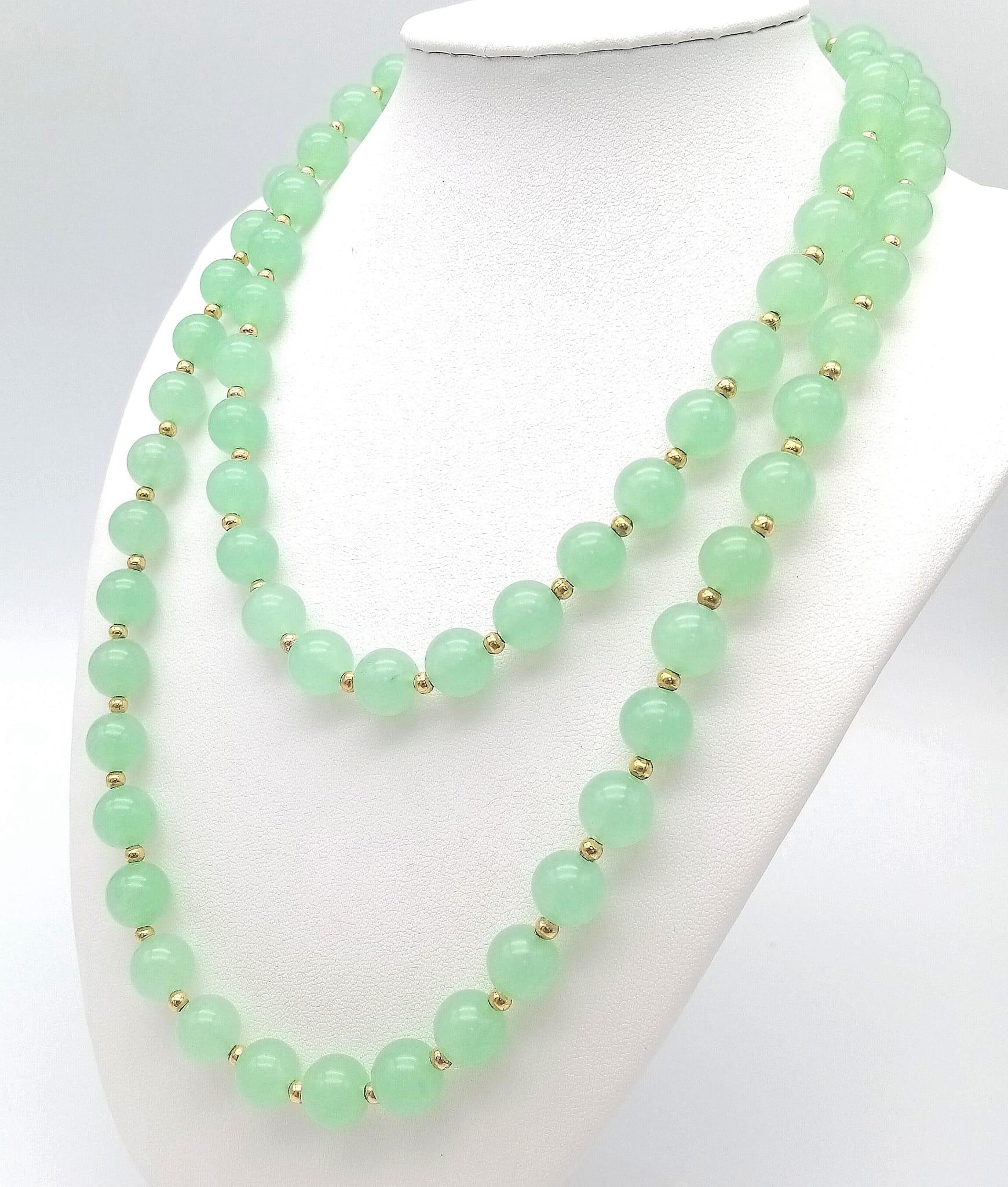 A Matinee Length Pale Green Jade Beaded Necklace. 10mm beads. Gilded spacers and clasp. 90cm