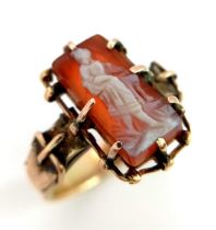 AN INTERESTING 9K YELLOW GOLD VINTAGE STONE SET RING. RECTANGULAR STONE CENTRE WITH CARVING OF A
