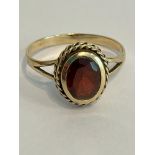 Classic style 9 carat GOLD RING set with an oval cut GARNET having an attractive GOLD ROPE surround.