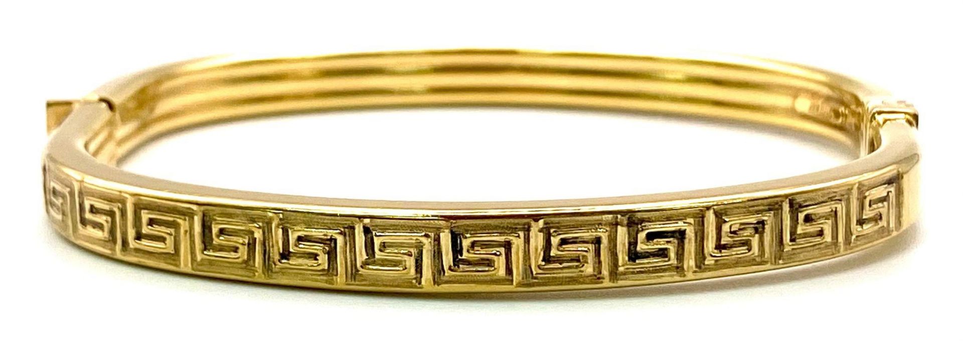 A 9K GOLD ITALIAN DESIGNER HINGED BANGLE WITH GREEK PATTERN ON ONE SIDE . 10.2gms