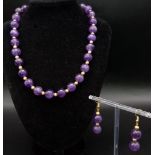 A fashionable, heavily gilded amethyst necklace and earrings set in a presentation case. Very good