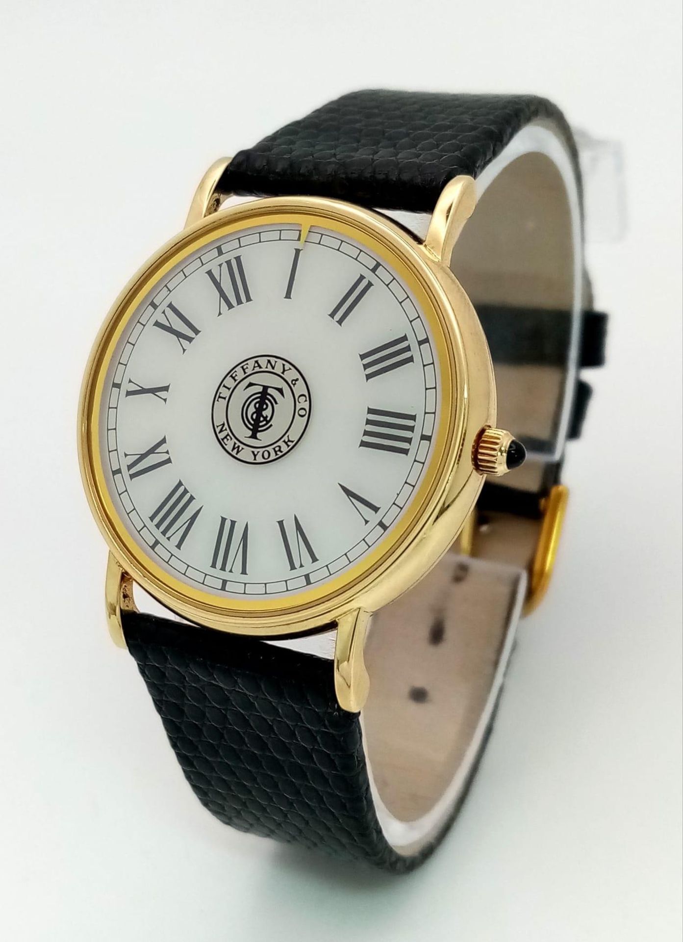 A Vintage 14K Gold Cased Tiffany and Co Ladies 'No Hands' Watch. Black leather strap. 14k gold