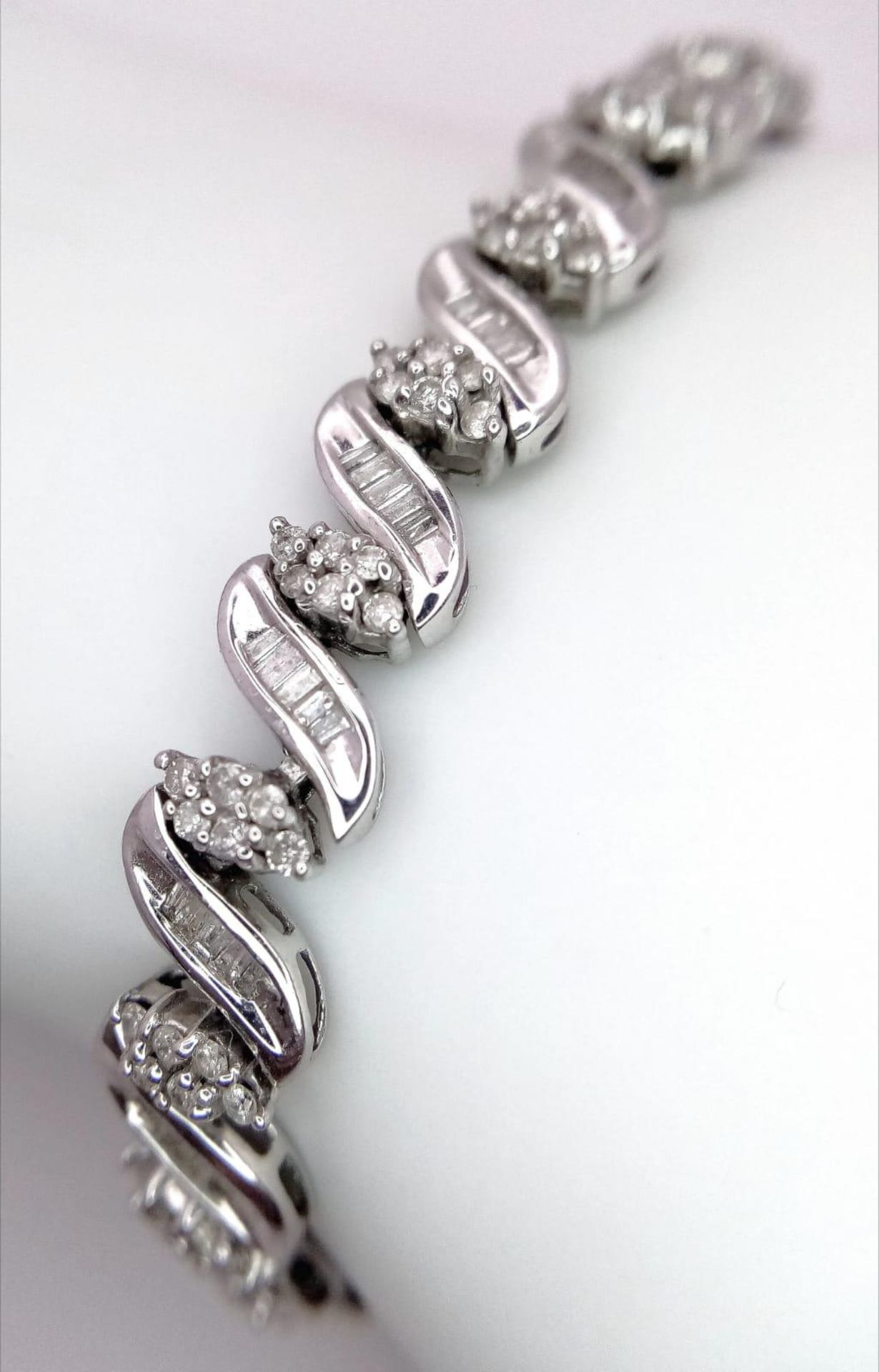 A 14K WHITE GOLD DIAMOND SWIRL BRACELET. A COMBINATION OF BAGUETTE AND ROUND CUT DIAMONDS 2.30CT