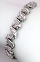 A 14K WHITE GOLD DIAMOND SWIRL BRACELET. A COMBINATION OF BAGUETTE AND ROUND CUT DIAMONDS 2.30CT