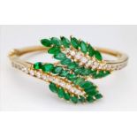 A DIAMOND AND EMERALD LEAF DESIGN BANGLE IN CROSSOVER STYLE SET IN18K GOLD . 33.5gms 10457