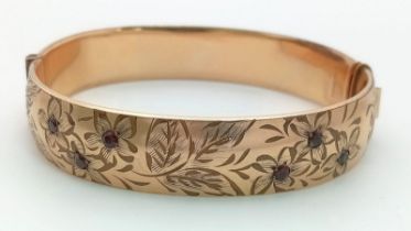 A vintage 9 K yellow gold engraved bangle with round cut garnets , width: 12.8 mm, weight: 22.4 g.