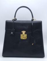 Black Gucci Top Handle Bag. Exotic, shiny lizard leather featuring gold toned hardware, flip-lock