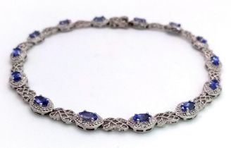 A 9K White Gold, Purple Sapphire and Diamond Tennis Bracelet. Eye-shaped links with sapphire