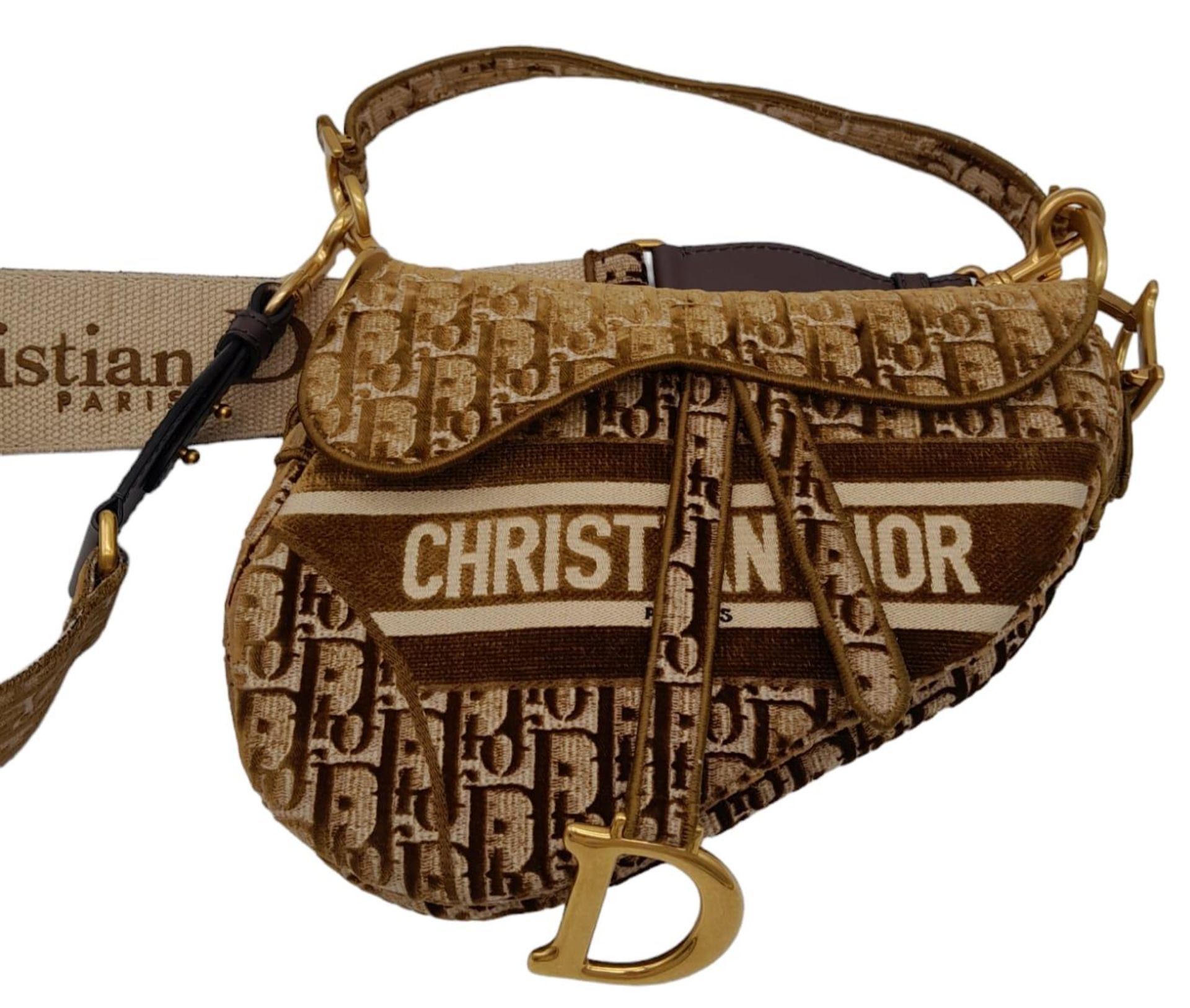 Christian Dior Saddle Handbag. Brown monogrammed velvet bag with gold tone hardware. Additional,