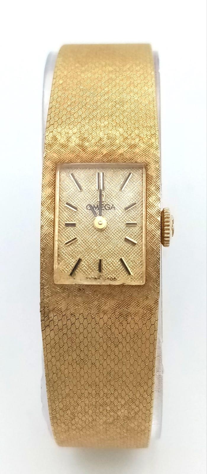 A VINTAGE LADIES 14K GOLD OMEGA CLASSIC 17 JEWELS MANUAL WIND WRIST WATCH WITH PATTERNED GOLD TONE