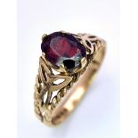 A Vintage 9K Yellow Gold and Garnet Ring. Central oval garnet set within pierced decoration. Size P.