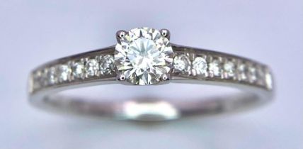 An 18K White Gold Diamond Ring. Central brilliant round cut diamond with diamonds on shoulders. 0.
