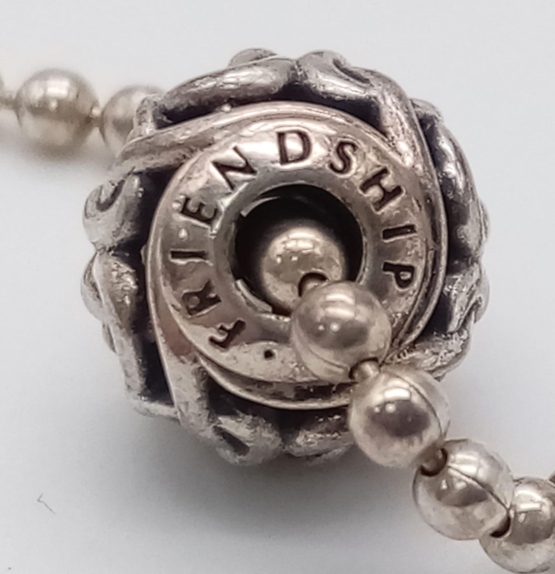 A sterling silver PANDORA friendship bracelet with two beads/charms. Weight: 6.8 g.