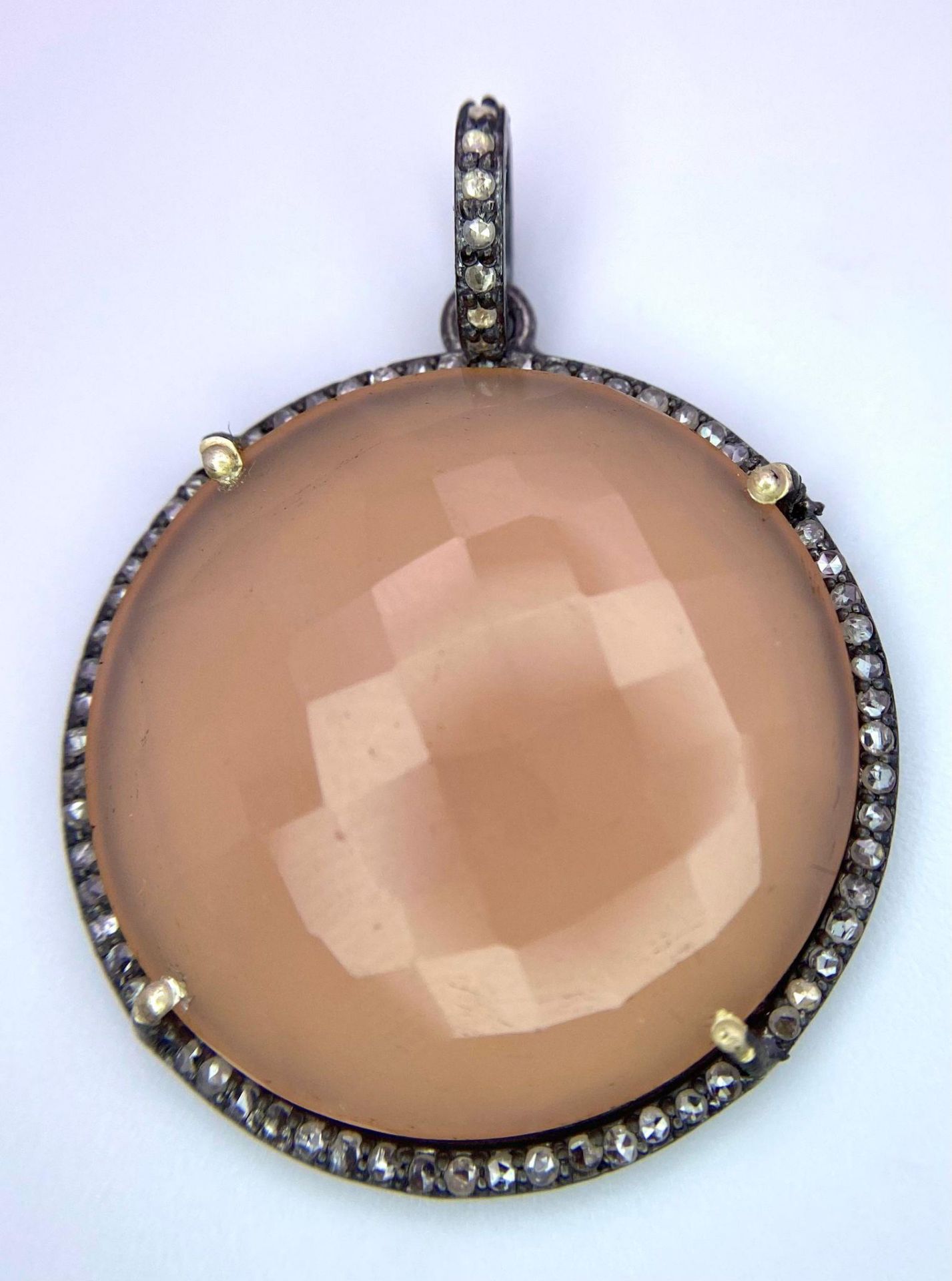 A Circular Rose Quartz and Diamonds Pendant. Faceted rose quartz cabochon with a diamond halo and
