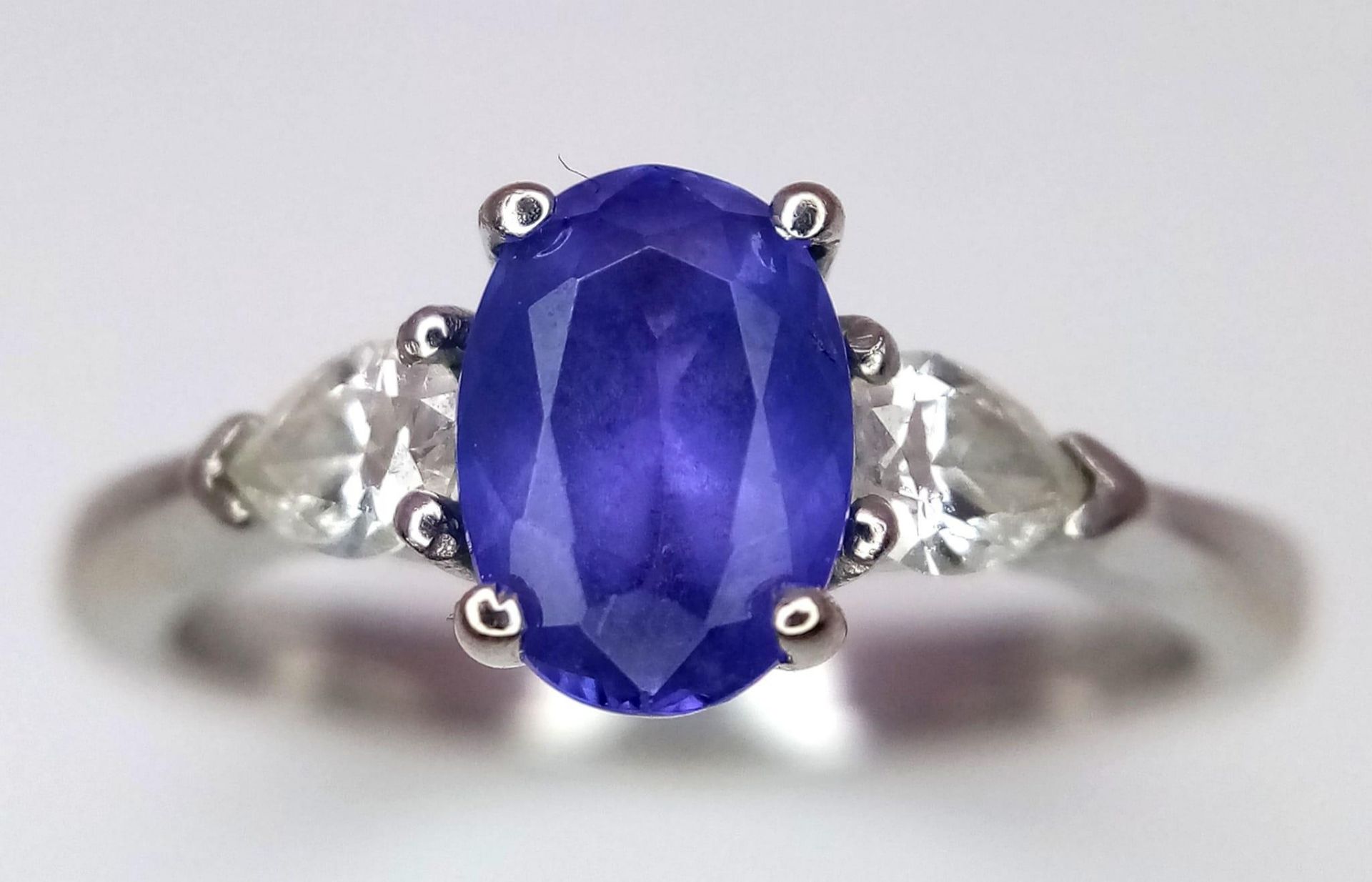 A 18K WHITE GOLD DIAMOND & TANZANITE 3 STONE RING. 0.50CT OF PEAR SHAPE DIAMONDS & 0.85CT OVAL