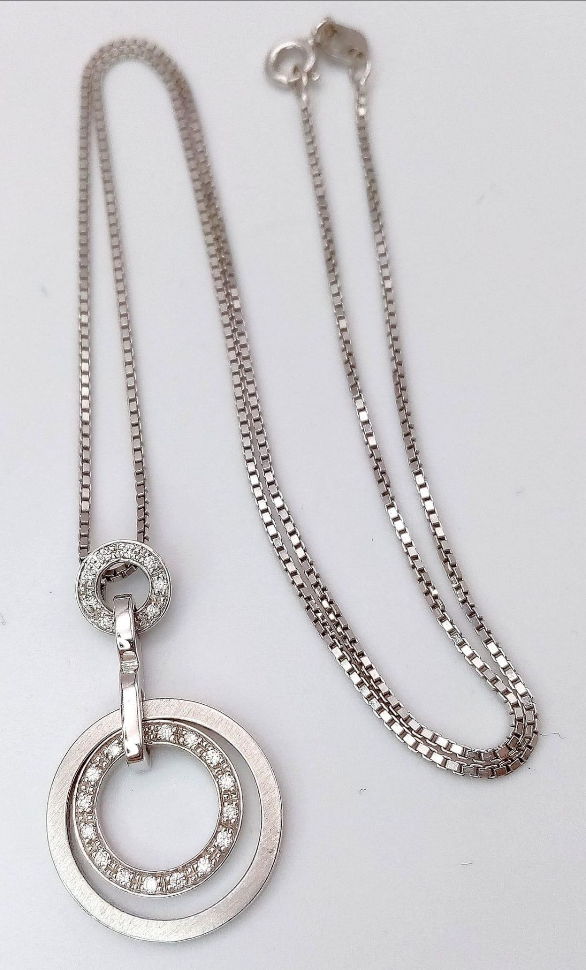 An 18K White Gold Diamond Set Circular Articulated Pendant on a Box Chain. 7.9g total weight. 16"