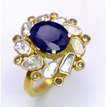 An eye-catching silver and gold ring with an oval cut blue sapphire surrounded by a group of large