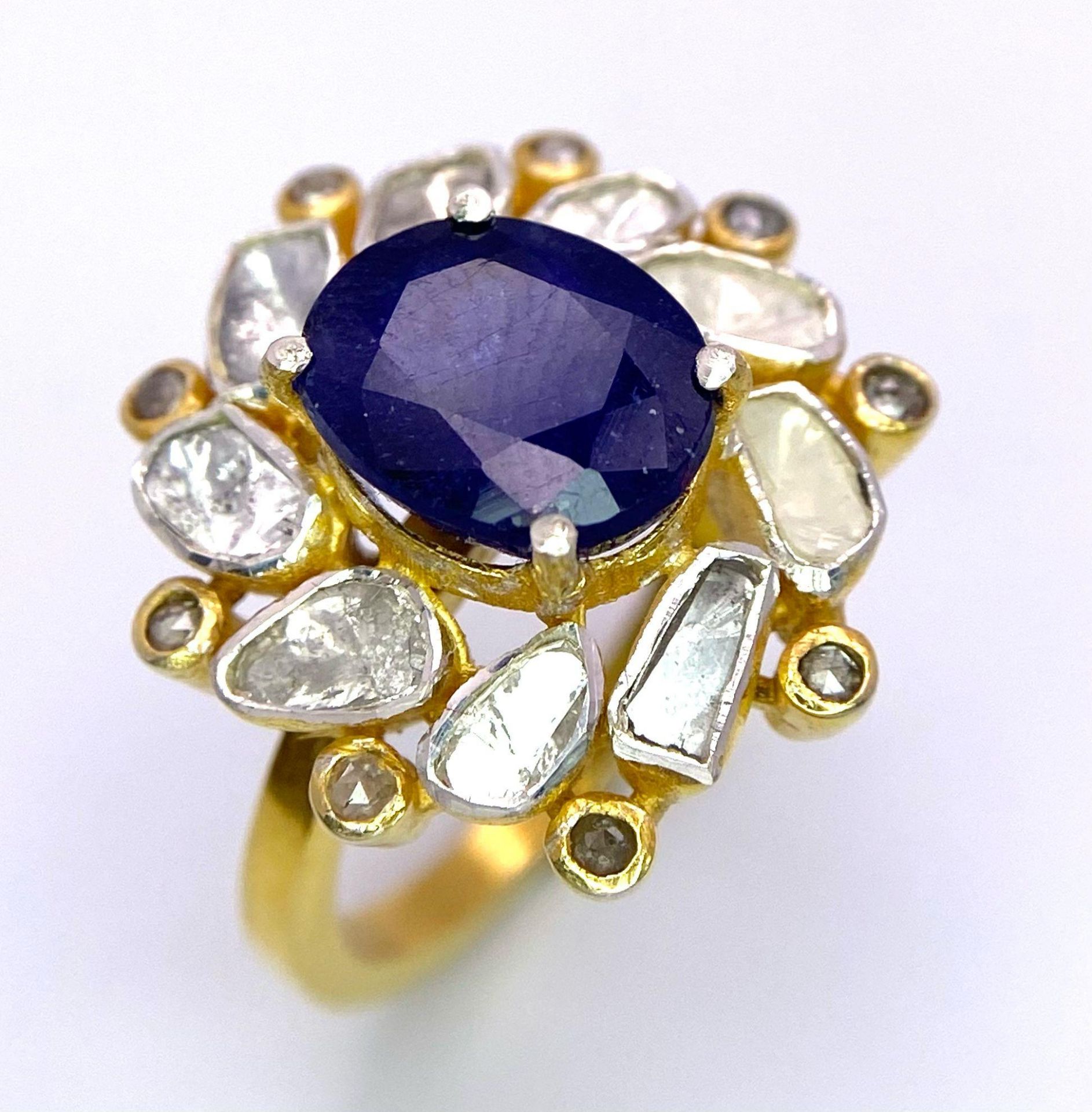 An eye-catching silver and gold ring with an oval cut blue sapphire surrounded by a group of large