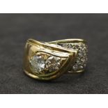 An 18kt Yellow Gold Ring with a duo of Round Cut Diamonds on one side, offset by a pavement of