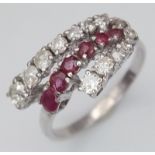 An 18K White Gold Ruby and Diamond Crossover Ring. Six round cut rubies in-between two rows of round