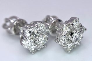 A Pair of 18K White Gold Diamond Floral Stud Earrings. Seven bright round cut diamonds in each. 2.8g
